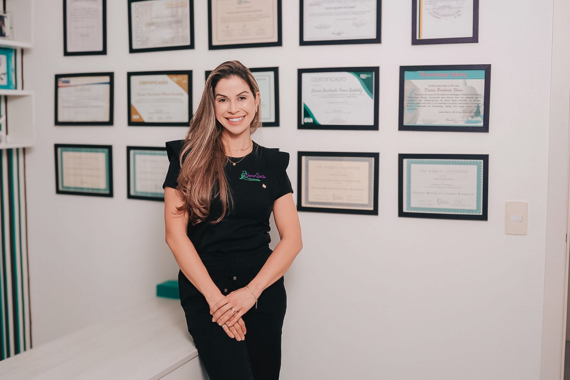 Dra. Daiane em frente à parede de certificações